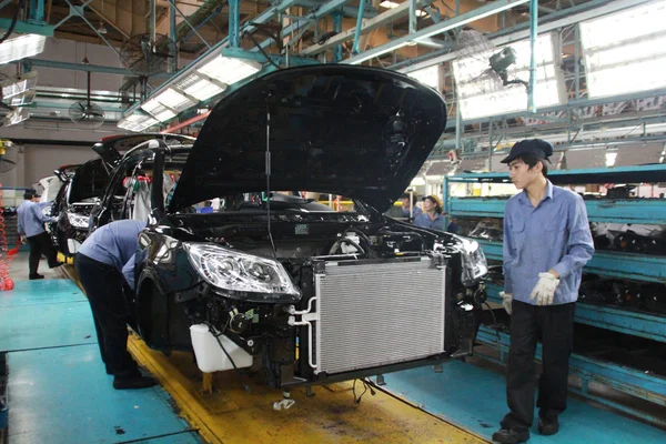 中国の労働者は 海南省海口市のファウハイマ自動車の自動車工場で組み立てラインに車を組み立てます 2014年3月11日 — ストック写真