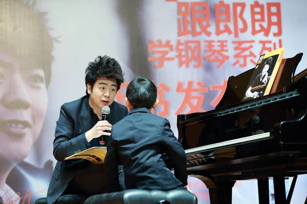 中国钢琴家郎朗 在2015年1月23日于中国上海为他的新书 郎朗钢琴学院 掌握钢琴 举行的新闻发布会上教了一个小男孩 — 图库照片