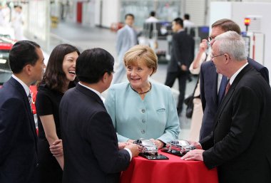 German Chancellor Angela Merkel, fourth left, reacts next to FAW Group Chairman Xu Jianyi, third left, Zhang Pijie, left, General Manager of FAW-Volkswagen, Volkswagen CEO Martin Winterkorn, right front, and Dr. Jochem Heizmann, right back, President clipart
