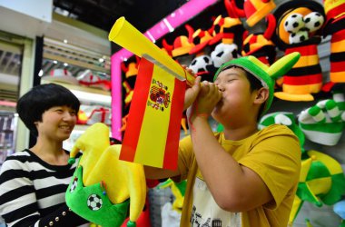 A young Chinese buyer blows a horn with a national flag of Spain produced for the 2014 Brazil World Cup in a shop at the Yiwu International Trade City in Yiwu city, east Chinas Zhejiang province, 6 May 2014. clipart