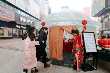 A Chinese waitress welcomes cutomers at the entrance of the hotpot restaurant made of ice blocks on the Taiyuan shopping street in Shenyang city, northeast China's Liaoning province, 20 January 2015 clipart