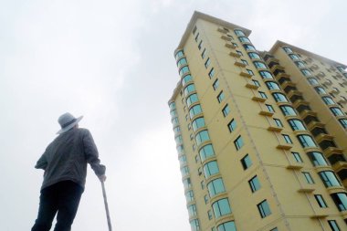 An elderly Chinese man looks at a newly-constructed high-rise residential apartment building in Anyang city, central Chinas Henan province, 16 September 2013 clipart
