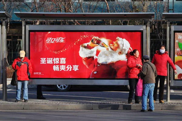 ファイル 乗客は 2013 日東北中国遼寧省瀋陽市のバス停でコカ コーラの広告の前で待ってください — ストック写真