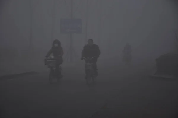 サイクリストは 中国山東省東部の梁川市で重いスモッグの道路に乗る 2014年1月30日 — ストック写真