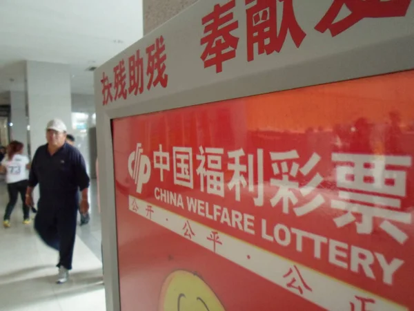 2013年6月15日 在中国东北黑龙江省齐齐哈尔市 一位行人走过中国福利彩票的招牌 — 图库照片