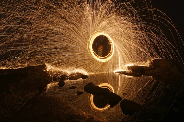 2014年6月24日 在中国东部山东省日照市的海滩上 一名游客在夜间旋转焰火 飞溅火花和制造火环 — 图库照片
