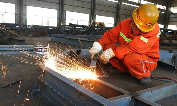 2014年5月13日 中国工人在中国东部山东省日照市一家机械设备厂加工钢铁产品 — 图库照片