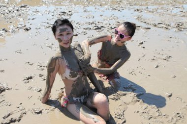 Young Chinese models who get muddy all over have fun in the mud on a tidal flat on the Xiushan Island in Daishan county, Zhoushan city, east Chinas Zhejiang province, 22 July 2014 clipart