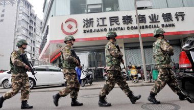 Armed Chinese paramilitary policemen walk past a branch of Zhejiang Mintai Commercial Bank as they patrol a street in Zhoushan city, east Chinas Zhejiang province, 5 March 2014 clipart