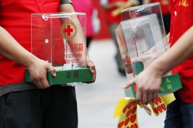 Chinese volunteers from the Shenzhen branch of the Red Cross Society of China holding nearly empty donation boxes ask pedestrians to donate money for the people in the quake-hit zone in southwest Chinas Sichuan province, on a street in Shenzhen city, clipart