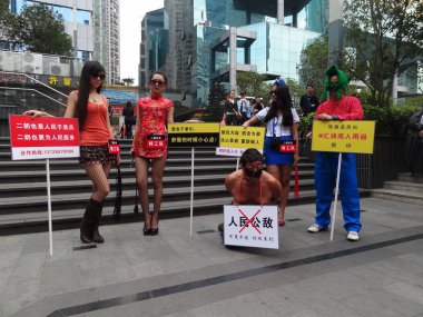 Three young ladies, acting as mistresses, and a middle-aged man, acting as a sacked corrupt official, play a performance art in front of the Grand Theatre in Shenzhen city, south Chinas Guangdong province, 22 January 2013 clipart