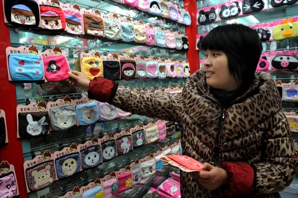 中国のベンダーは 2013年1月15日 中国浙江省東部のYiwu市のYiwu国際貿易都市の店で漫画のフェイスマスクを調整します — ストック写真