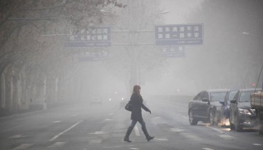 A pedestrian walks across a road in heavy fog in Jinan city, east Chinas Shandong province, 13 January 2013 clipart