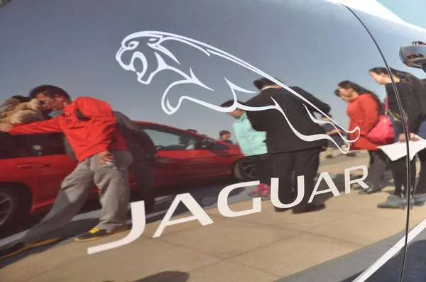 Visitors look at Jaguar cars during an auto show in Qingdao city, east Chinas Shandong province, 14 April 2013.