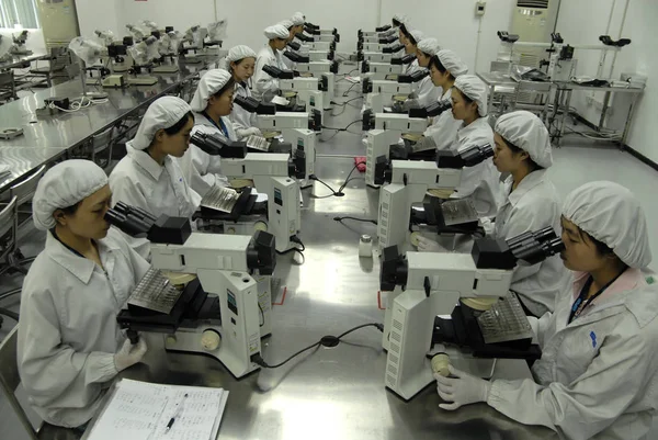 2010年3月20日 中国広東省東莞市の工場で研修中に顕微鏡を操作する若い女性中国人新入労働者 — ストック写真
