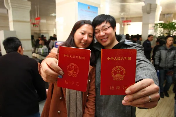 中国人カップルが2013年1月4日 中国南部雲南省の京市の婚姻届事務所で婚姻証明書を見せる — ストック写真
