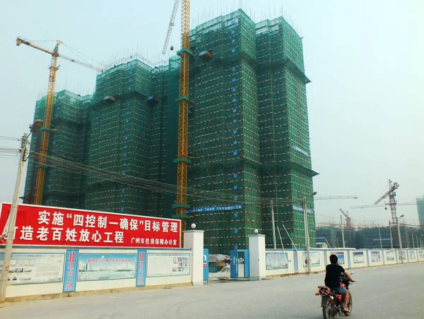 2012年8月29日 中国南部広東省広州市の新しい住宅マンションプロジェクトの建設現場を通り過ぎるオートバイに乗る男 — ストック写真