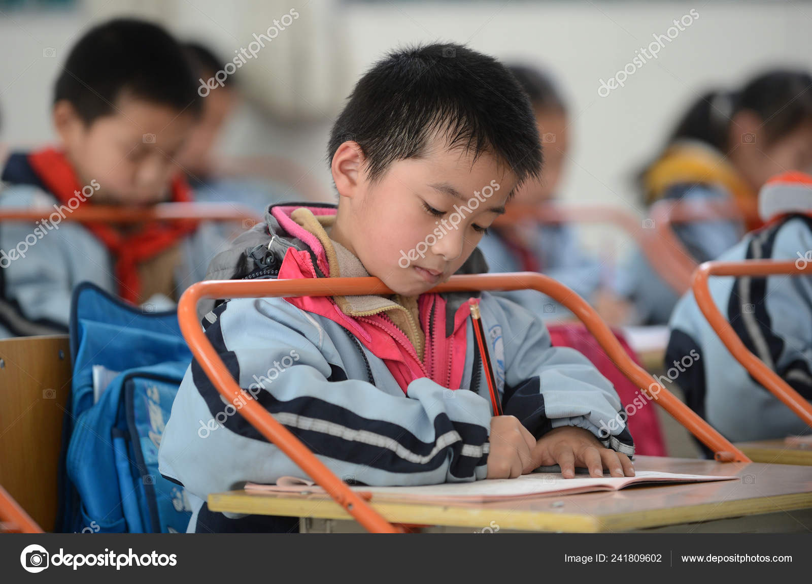 2014年3月10日 中国中部湖北省武漢市の小学校の教室に適切な距離を保つためにバーを設置した机の上に宿題を書く中国人の男子生徒 —  ストック編集用写真©IC Photo#241809602, image size:1600x1150