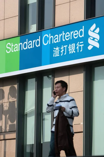 2012年3月31日 一名行人在伦敦上市的渣打银行 Standard Chartered Bank 中国上海分行门前使用手机 — 图库照片