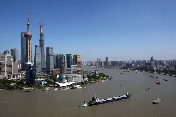 Boats sailing along the Huangpu River pass by the Lujiazui Financial District with the Shanghai Tower under construction, the Oriental Pearl TV Tower, tallest, the Shanghai World Financial Center and other skyscrapers and high-rise buildings in Pudon