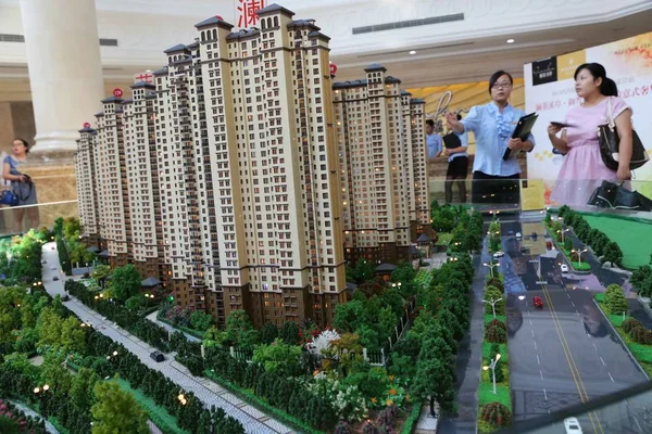 2013年7月16日 在中国中部河南省许昌市一住宅公寓项目销售中心 一位中国女售货员在住宅模型旁与购房者交谈 — 图库照片