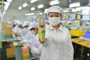 A Chinese worker shows an electronic cigarette in the packaging workshop at the plant of Huizhou Kimree Technology Co., Ltd. in Huizhou city, south China's Guangdong province, 3 March 2014 clipart