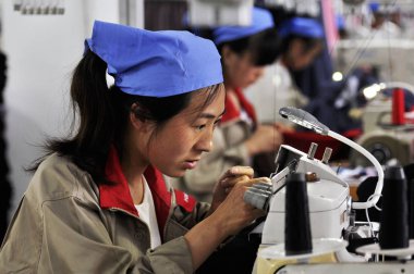 female Chinese workers sew clothes at a garment factory in Jimo city, east Chinas Shandong province, 24 May 2014 clipart