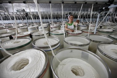 female Chinese worker handles production of yarn to be exported to Europe at a textile factory in Huaibei city, east Chinas Anhui province, 8 July 2014. clipart