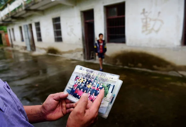 中国人教師のXie Daoyuは 2014年8月31日 中国東部の安寧省 フェイドン郡バイロン町の三河小学校で 彼の唯一の生徒の王海西の隣で2003年4月に撮影された生徒と教師の集合写真を示しています — ストック写真