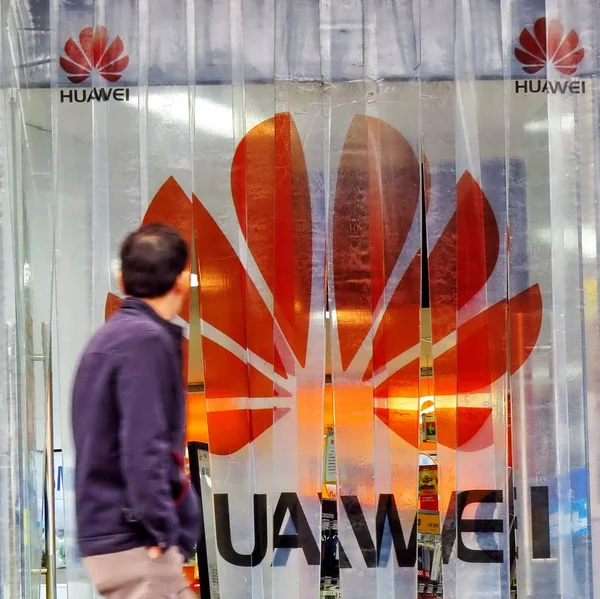 2013年2月26日 在中国上海的一家商店里 一位行人走过华为的标志 — 图库照片