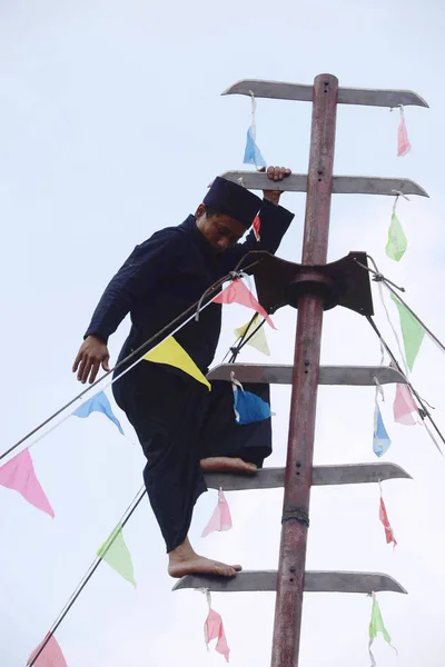 中国のLisu少数民族の男性は 2014年9月6日 中国東部山東省青島市の青島森林野生動物の世界で裸足で羽根のはしごを登ります — ストック写真