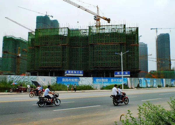 ファイル サイクリストはイーチャン市の建設中の高層住宅マンションを過ぎた中国 湖北省中央部 月2014 — ストック写真