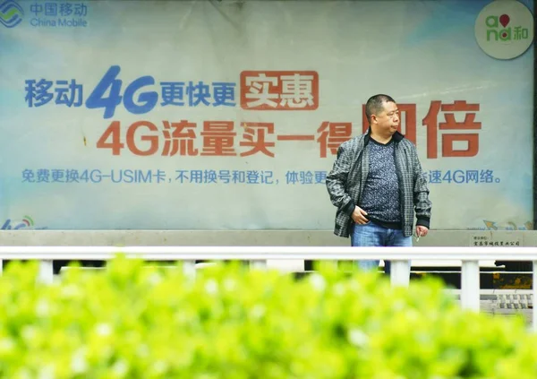 File 歩行者は 中国中央部湖北省の中国モバイルの4G Lteネットワークの広告の前に立っています 2014年3月28日 — ストック写真