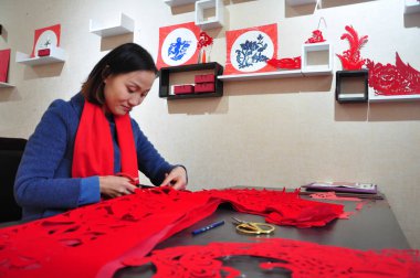 Chinese craftswoman Liang Ying displays cheongsam (qipao) made of paper-cuttings to greet the upcoming Chinese Lunar New Year or Spring Festival at her studio in Liaocheng city, east China's Shandong province, 30 January 2019 clipart