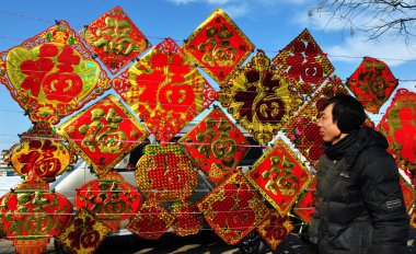 A pedestrian walks past red decals for sale at a stall for the Chinese Lunar New Year, or Spring Festival, in Zibo city, east Chinas Shandong province, 7 February 2013 clipart