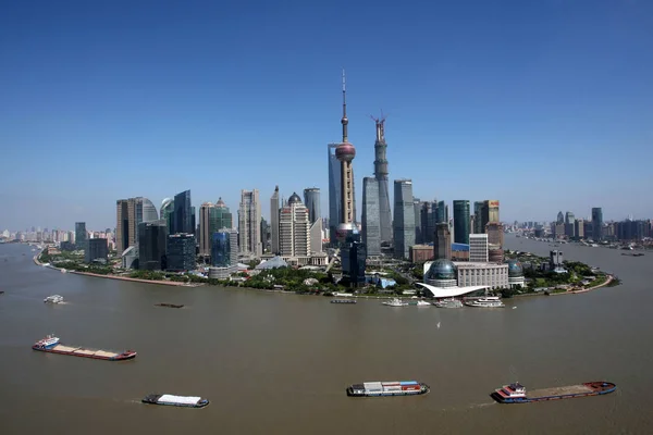 Boats sailing along the Huangpu River pass by the Lujiazui Financial District with the Shanghai Tower under construction, the Oriental Pearl TV Tower, the Shanghai World Financial Center and other skyscrapers and high-rise buildings in Pudong, Shangh