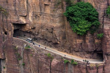 A minivan passes by people wallking along the Guoliang Tunnel through the Wanxian Mountain in the Taihang Mountains in Huixian county, Xinxiang city, central China's Henan province, 3 May 2007 clipart