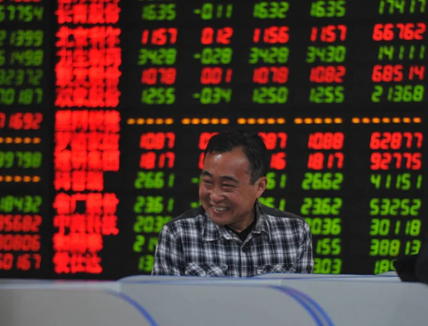 Китайский Инвестор Улыбается Перед Экраном Показывая Акции Красный Роста Цен — стоковое фото