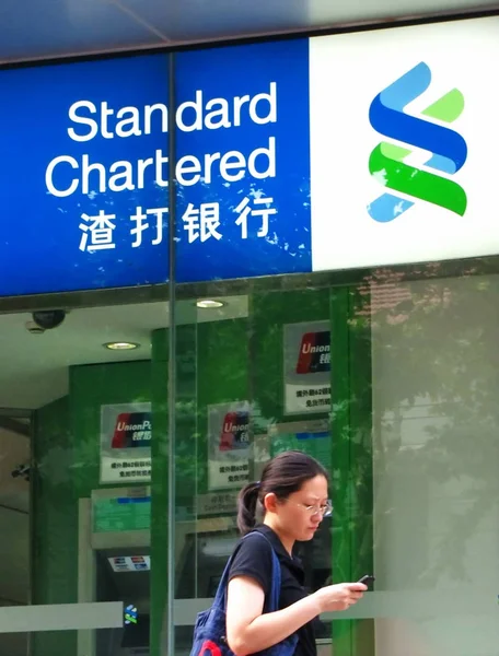 2011年7月26日 一位行人走过渣打银行 位于中国上海的分行时 看着她的手机 — 图库照片
