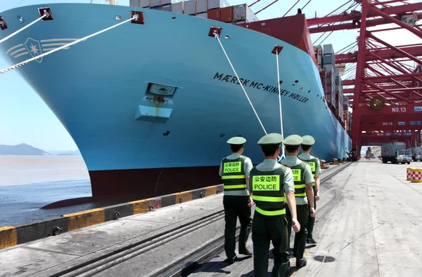 Chinese public securities walk past the Maersk Mc-Kinney Moeller Triple-E class container vessel, the worlds largest ship as it arrives at the Ningbo port in Ningbo, east Chinas Zhejiang province, 20 July 2013 — Stock Image Chinese Public Securities Walk Maersk Kinney Moeller Triple Class Container Royalty Free Stock Images
