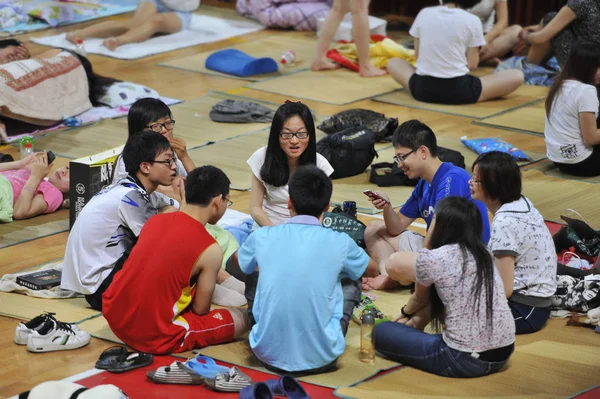 College students sitting on bamboo/straw mats at a air-conditioned school gym to escape the sweltering heat in their dorms, which are not air-conditioned, in Wuhan, central Chinas Hubei province, 21 June 2013