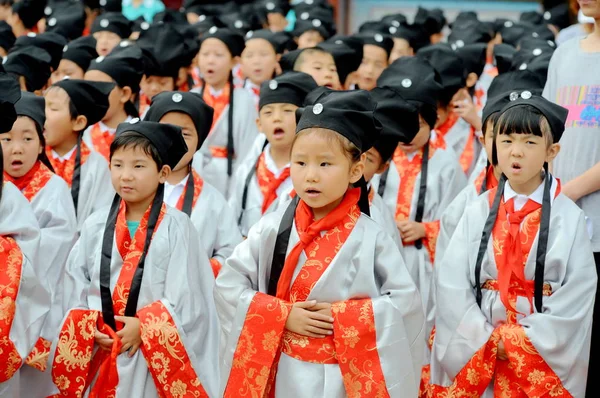 古代中国の学生衣装を着た若い生徒たちは 中国甘粛省北西部の蘭州市の教師の日に修小学校での除幕式の際に孔子像の前で 孔子の類似点 を暗唱します — ストック写真