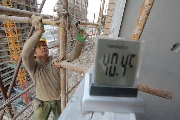 Chiński Pracownik Migrujący Buduje Rusztowania Obok Termometru Odczytem Stopni Celsjusza — Zdjęcie stockowe