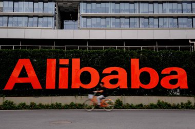 A cyclist rides past a signboard of Alibaba Group in Hangzhou city, east Chinas Zhejiang province, 25 June 2014 clipart