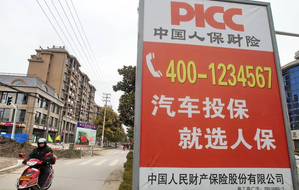 2013年3月3日 一名骑自行车的人在中国江苏省南通市经过 Picc 财产与伤亡有限公司的广告 — 图库照片