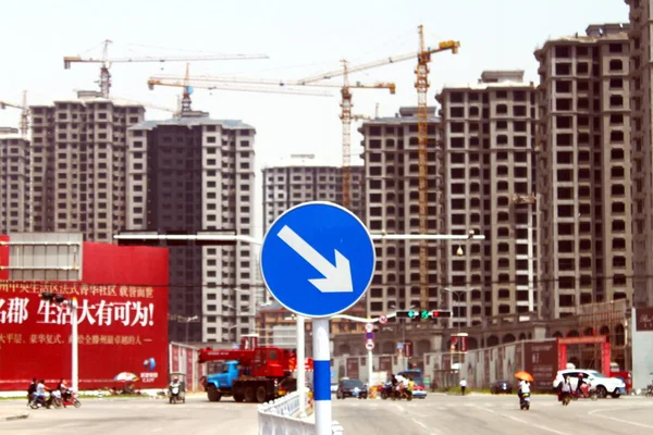 下向き矢印の付いた交通標識は 2014年5月27日 中国東部山東省済南市で建設中の新しい高層住宅マンションの近くに描かれています — ストック写真