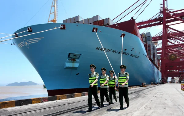 Chinese public securities walk past the Maersk Mc-Kinney Moeller Triple-E class container vessel, the worlds largest ship as it arrives at the Ningbo port in Ningbo, east Chinas Zhejiang province, 20 July 2013 — Stock Image Chinese Public Securities Walk Maersk Kinney Moeller Triple Class Container Stock Picture