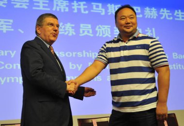 Thomas Bach, president of the International Olympic Committee (IOC), left, shakes hands with retired Chinese badminton player Zhangjun during an award ceremony at the Nanjing Sport Institute (NSI) in Nanjing city, east Chinas Jiangsu province, 19 Aug clipart