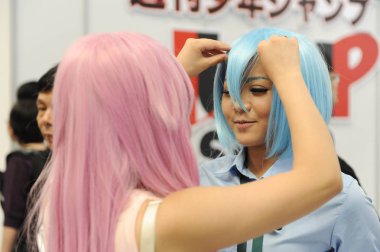 A showgirl dressed in a cosplay costume adjusts the wig of another during the 9th China International Cartoon and Games Expo, known as CCG Expo 2013, in Shanghai, China, 11 July 2013 clipart