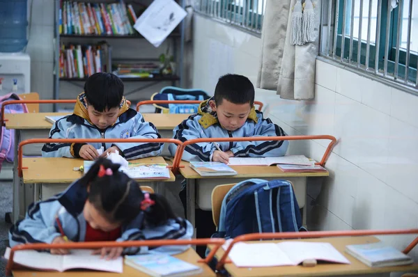2014年3月10日 中国武汉市武汉市一所小学的教室里 中国小学生在课桌上写作业 并安装了酒吧 以保持适当的距离 — 图库照片
